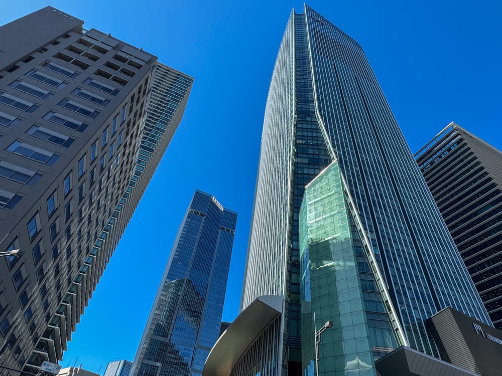 Low-angle view of two modern glass office buildings against a blue sky